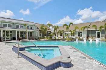 A swimming pool surrounded by a tiled patio and a building with a glass facade.